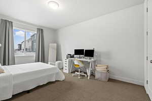 Bedroom featuring light colored carpet and an office area