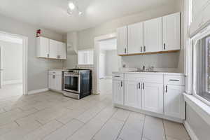 Kitchen with white cabinets, light countertops, and stainless steel range with gas cooktop