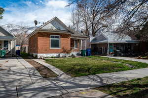 View of front facade featuring brick siding, a front lawn, covered porch, and a mountain view