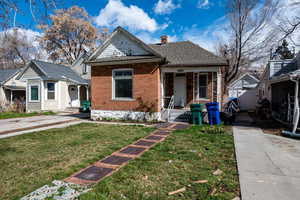 View of front of house featuring a front yard, a chimney, and brick siding