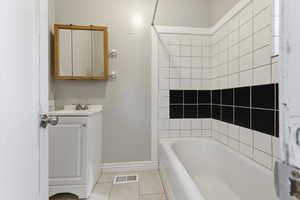 Full bath featuring vanity, light tile patterned flooring, and tub / shower combination