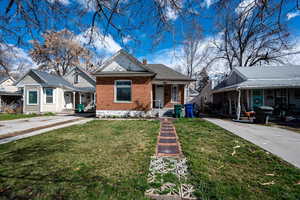 View of front of property featuring covered porch, a front yard, a chimney, and brick siding