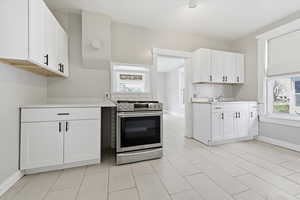 Kitchen with stainless steel gas range oven and white cabinets