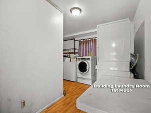 Shared laundry room with light wood-style flooring and washing machine and dryer