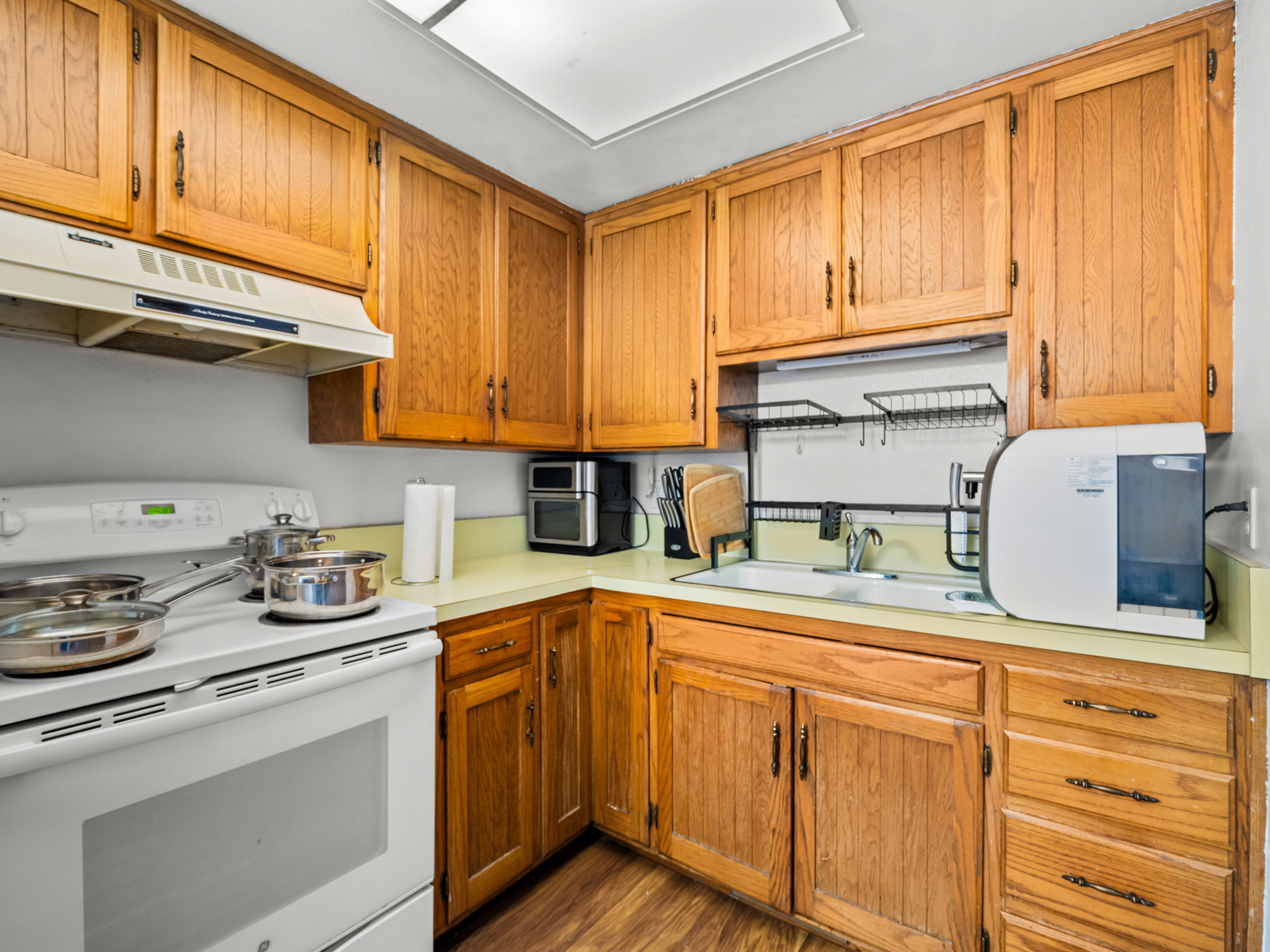 Kitchen with electric range, light countertops, wood finish cabinets, and dark wood finished floors