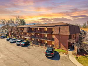 Property at dusk featuring uncovered parking and a view of apartment building / complex