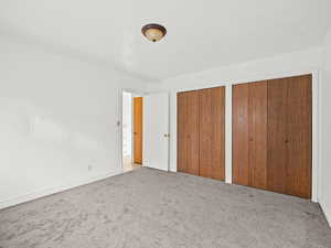 Unfurnished bedroom featuring two closets and light carpet