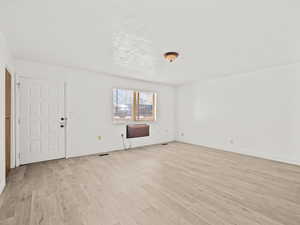 Unfurnished living room with light wood-type flooring and baseboards