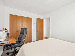 Bedroom featuring a closet, a desk, a textured ceiling, and carpet floors