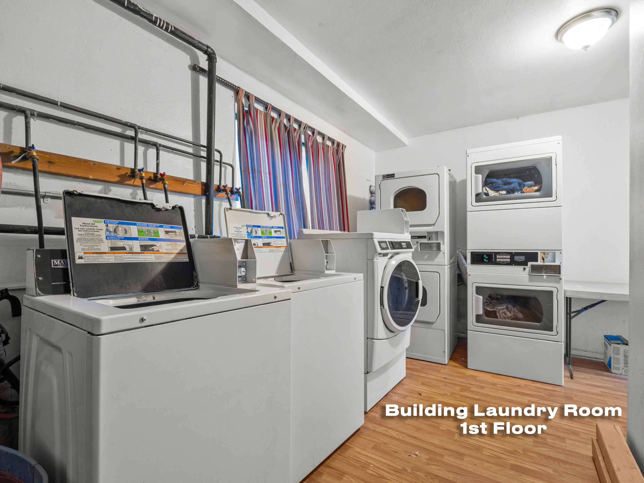 Shared laundry room with light wood-type flooring, separate washer and dryer, and stacked washing machine and dryer
