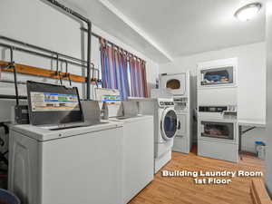 Shared laundry room with light wood-type flooring, separate washer and dryer, and stacked washing machine and dryer