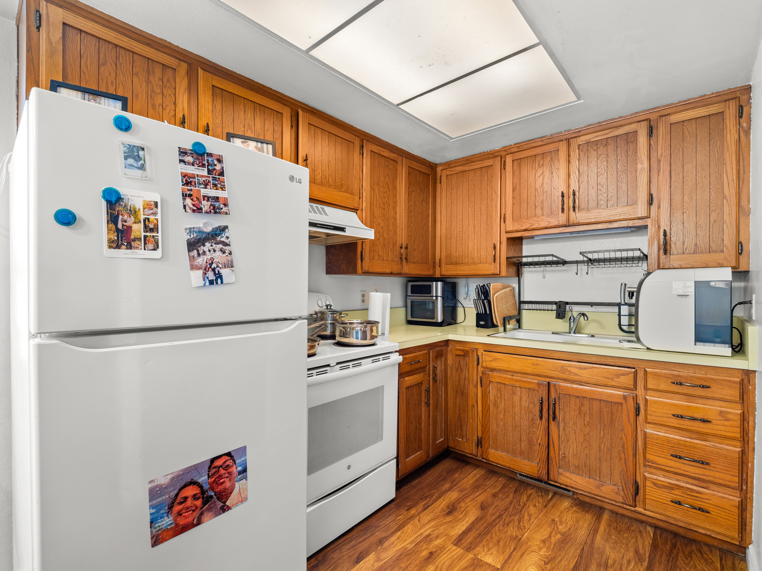 Kitchen featuring white appliances, light countertops, dark wood finished floors, and wood finish cabinets
