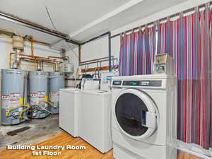Community laundry room with separate washer and dryer, water heater, and secured water heater