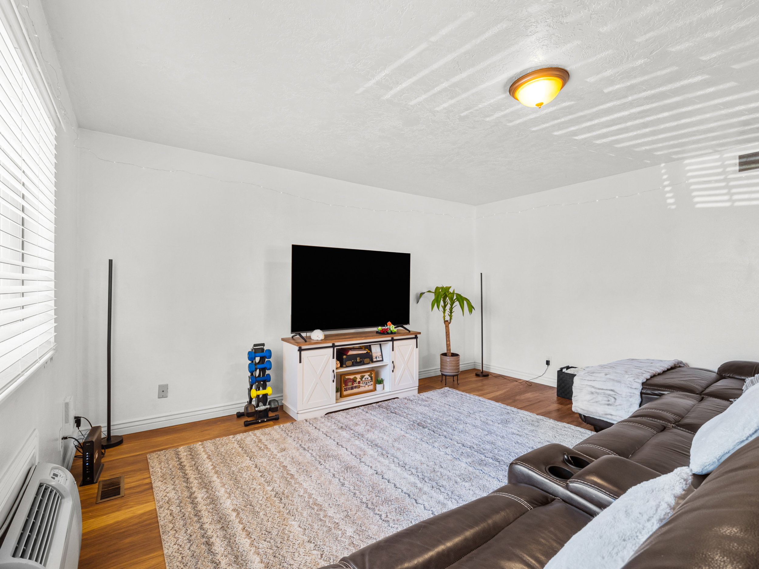 Living area with a wall mounted air conditioner and dark wood finished floors
