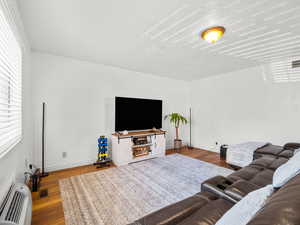Living area with a wall mounted air conditioner and dark wood finished floors