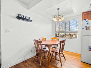 Dining space with light wood-style floors, suspended lighting, and a raised ceiling