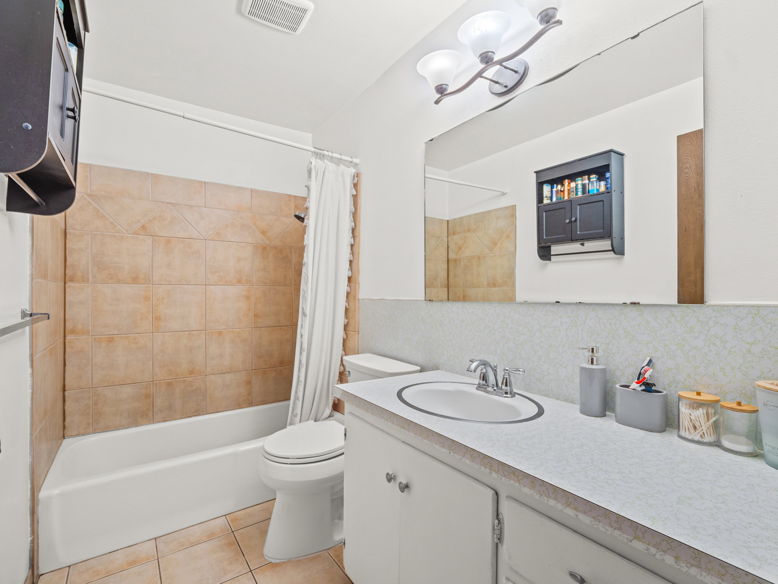 Full bathroom featuring vanity, shower / tub combo with curtain, light tile patterned flooring, and tasteful backsplash