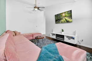 Living room featuring ceiling fan and dark wood-style floors