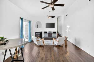 Living area with a glass covered fireplace, dark wood-style floors, and ceiling fan