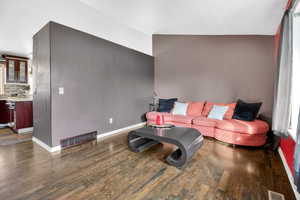 Living room featuring dark wood-style floors and vaulted ceiling