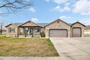 Ranch-style home featuring a porch, a garage, driveway, and brick siding