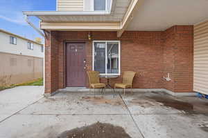 Entrance to property with brick siding and a patio