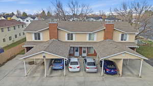 View of front of home featuring roof with shingles, a chimney, covered parking, and a residential view
