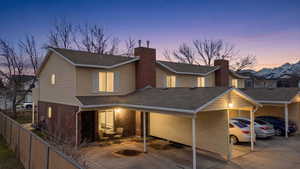 View of front of house with roof with shingles, brick siding, and a patio