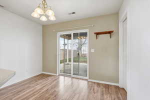 Unfurnished dining area featuring suspended lighting and light wood-style floors