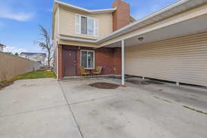 Entrance to property featuring a chimney, brick siding, and a patio