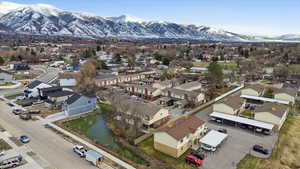 Aerial view of property and surrounding area featuring mountains and nearby suburban area