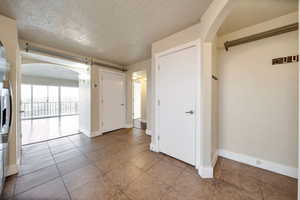 Spare room with arched walkways, a textured ceiling, and light tile patterned flooring