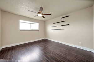Empty room featuring dark wood finished floors, a textured ceiling, and ceiling fan
