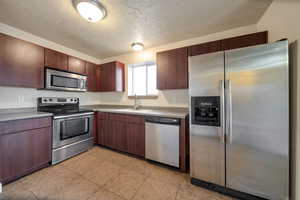 Kitchen featuring stainless steel appliances, a textured ceiling, light countertops, and light tile patterned flooring