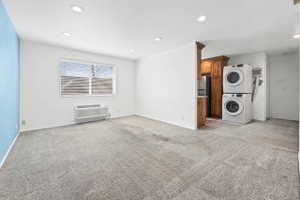 Unfurnished living room with stacked washer / drying machine, light carpet, and recessed lighting