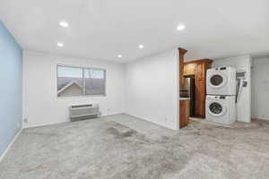 Laundry area featuring stacked washer and dryer, recessed lighting, and light carpet