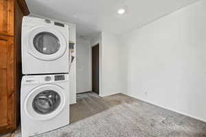 Laundry area with carpet floors and stacked washer / dryer