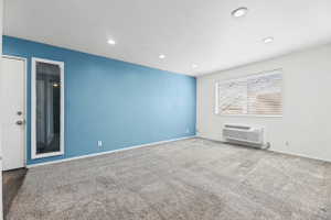 Carpeted spare room featuring a ptac unit and recessed lighting