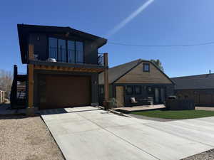 View of front of house with concrete driveway, an attached garage, and a balcony