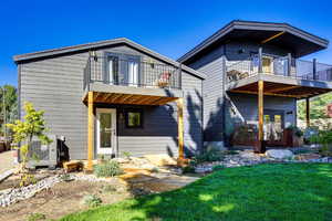 Rear view of house featuring a balcony, a yard, and a patio