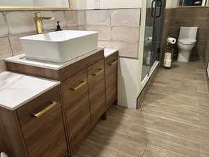 Bathroom with tile walls, vanity, wood tiled floors, and a stall shower