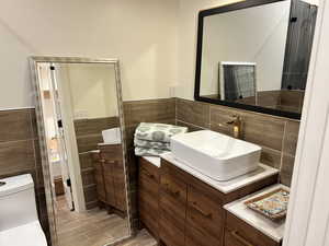 Bathroom featuring tile walls, vanity, wainscoting, and wood finish floors