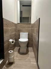 Bathroom featuring tile walls and toilet