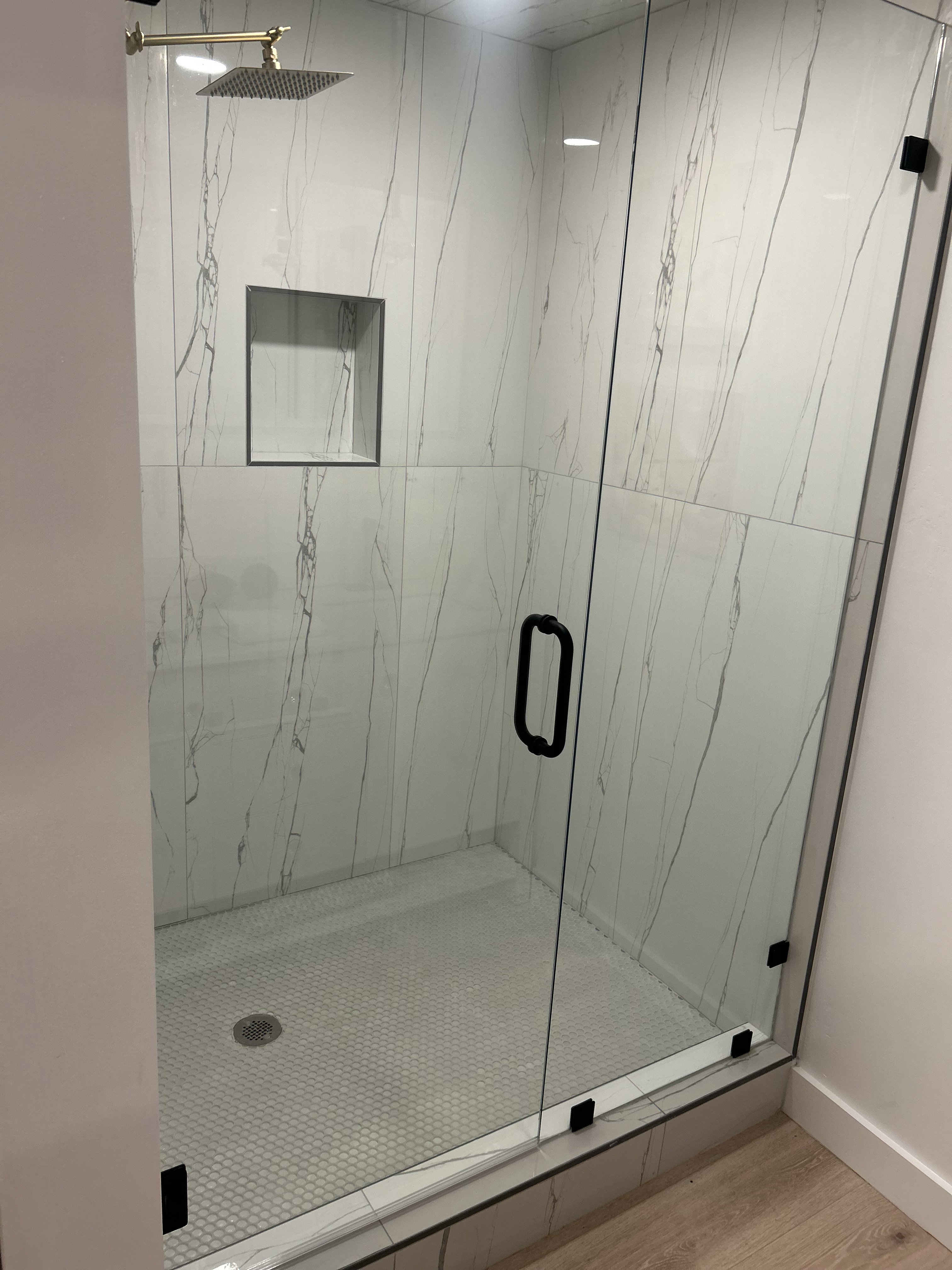 Full bath featuring a marble finish shower and light wood-style floors
