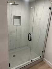 Full bath featuring a marble finish shower and light wood-style floors