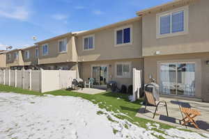 Snow covered house with a patio and stucco siding