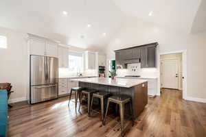 Kitchen featuring stainless steel appliances, a kitchen breakfast bar, a kitchen island, a high ceiling, and dark wood finished floors