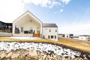 Snow covered back of property with a metal roof and a wooden deck