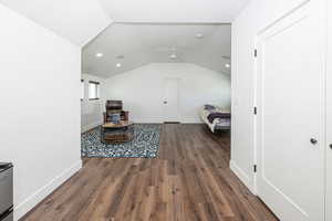 Living area with dark wood finished floors, vaulted ceiling, and recessed lighting