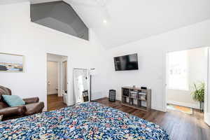 Bedroom featuring dark wood-type flooring, vaulted ceiling, a ceiling fan, and ensuite bath